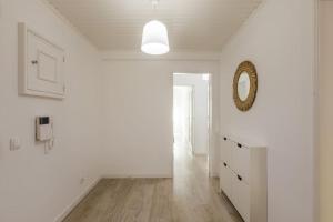 un couloir blanc avec un miroir et un mur blanc dans l'établissement Massamá 26 / free park on premises/ smart TV, à Queluz