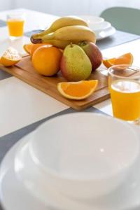 a plate of fruit with bananas and oranges on a table at Massamá 26 / free park on premises/ smart TV in Queluz