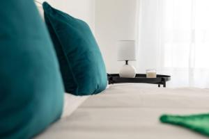 łóżko z zielonymi poduszkami oraz stół z lampką w obiekcie Massamá 26 / free park on premises/ smart TV w mieście Queluz