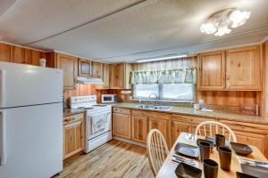 a kitchen with wooden cabinets and a white refrigerator at Eufaula Retreat Community Pool and Screened Porch! in Eufaula