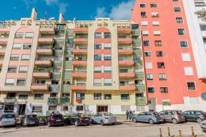 un gran edificio de apartamentos con coches aparcados en un aparcamiento en Massamá 26 / free park on premises/ smart TV, en Queluz