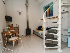 uma sala de estar com uma escada em espiral e uma secretária em Puffins Nest em Bideford