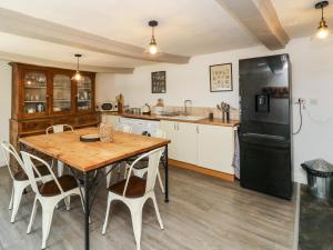 - une cuisine avec une table en bois et un réfrigérateur noir dans l'établissement Puffin House, à Bideford