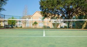 a tennis court with a net in front of a house at Sweet retreat condo resort in Kissimmee