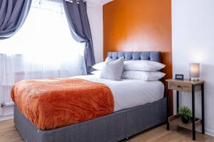 a bedroom with a large bed with an orange wall at 2 Bed House near the London Museum in London
