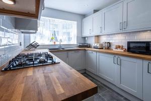 a kitchen with white cabinets and a stove top oven at 2 Bed House near the London Museum in London