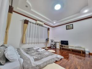 a living room with a bed and a television at Palmy House Homestay Udonthani in Udon Thani