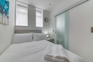 a bedroom with a white bed and two windows at Superior Compact Studio Close to Amenities in Leeds