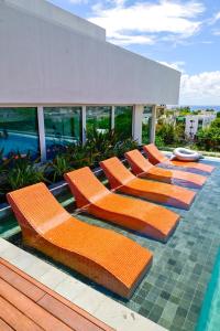een rij oranje stoelen naast een zwembad bij Aloft Playa del Carmen in Playa del Carmen