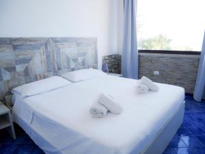1 dormitorio con 1 cama blanca grande y toallas. en Al Vecchio Pontile bed and breakfast, en Marsala