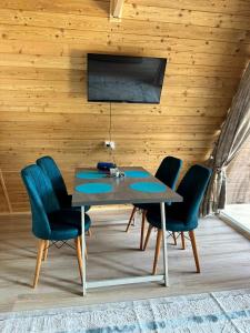 a dining room table with blue chairs and a television at AFrame_Kolsai in Saty