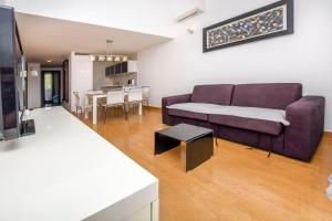 a living room with a purple couch and a kitchen at Apartment Marin in Rogoznica