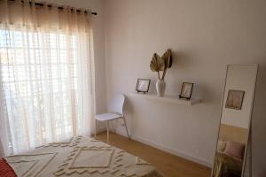 Habitación blanca con silla y ventana en Apartamento para férias-Nazaré, en Nazaré