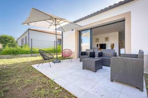 une terrasse avec un canapé, un parasol et des chaises dans l'établissement -Golden jungle- Splendide maison neuve / climatisation/ dressing/ jardin, à Montussan