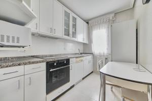 a white kitchen with white cabinets and a stove top oven at Jardines del Ebro, 8 Pax, ideal grupos y centrico in Logroño