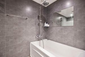 ein Bad mit einer Badewanne und einem Spiegel in der Unterkunft HERTZ Hotel in Seoul
