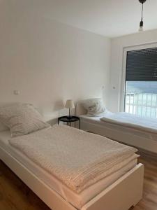 a white bedroom with two beds and a window at Ganzes Apartment -London- in Erftstadt - 3 Zimmer & 63qm - nahe Köln, Messe, Phantasialand & Bonn - Familienurlaub oder Business Trip in Erftstadt
