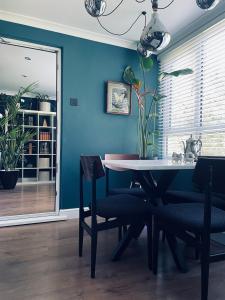 een eetkamer met blauwe muren en een tafel en stoelen bij Luxury mid century Apartment in Londen