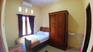 a small bedroom with a bed and a wooden cabinet at Eltanin Homestay by FH Stay in Salakan