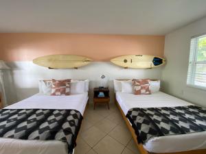 Seaspray Surf Lodge في فيرو بيتش: سريرين في غرفة مع ألواح ركوب الأمواج على الحائط