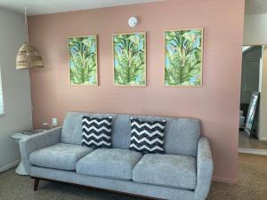 a living room with a couch and three paintings on the wall at Seaspray Surf Lodge in Vero Beach