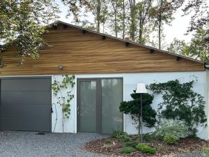 a white garage with a wooden roof at Une parenthèse à la Sarte (wellness) in Huy