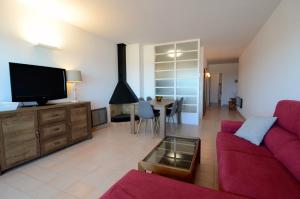 ein Wohnzimmer mit einem roten Sofa und einem TV in der Unterkunft Puig Padro 4 1-1 in L'Escala