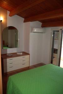 een slaapkamer met een groen bed en een spiegel bij Casa Adelaide in Santa Croce Camerina