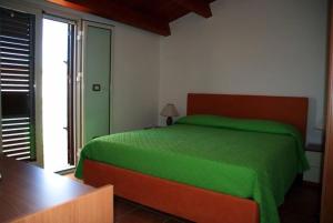 een slaapkamer met een groen bed en een raam bij Casa Adelaide in Santa Croce Camerina