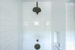 a white tiled shower with a toilet in it at 1907 Stone House - King Bed, Office, Crib, Toys in San Diego +43 photos