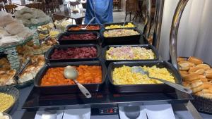 a buffet filled with trays of different types of food at Ímpar Suítes Cidade Nova in Belo Horizonte