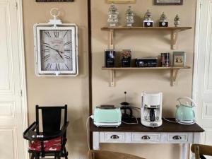 Zimmer mit einem Tisch und einer Uhr an der Wand in der Unterkunft Charmant Gîte Familial avec Jardin Privatif et Confort Moderne, au Cœur de la Touraine - FR-1-381-550 in Sepmes