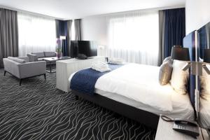 une chambre d'hôtel avec un lit et un salon dans l'établissement Van der Valk Hotel Mons Congres, à Mons