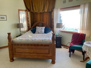 a bedroom with a bed and a chair and a window at Rocky Mountain View Bed & Breakfast in Cochrane
