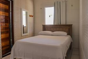 ein Schlafzimmer mit einem Bett mit zwei Kissen und einem Fenster in der Unterkunft Pousada Farol da Barra in Tutóia