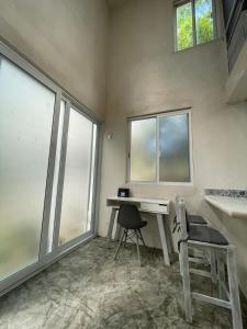 Habitación con escritorio, silla y ventanas. en Tulum Loft, en Tulum
