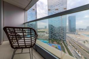 a chair in a room with a large window at Capital Living On Reem - The Arc Towers & The Gate in Abu Dhabi