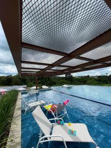 a person sitting in a chair next to a swimming pool at Resort em pirinopolis in Pirenópolis