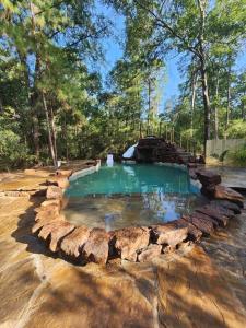 a large pool of water with rocks around it at Waterfront Treehouse in a Magical Forest in Waller