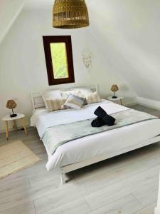 a white bedroom with two beds and a window at S'Hiesele petite maison alsacienne typique in Ittenheim