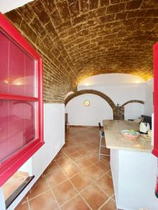 cocina con pared de ladrillo y ventana roja en Casa da Moeda en Évora