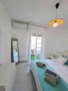 a white bedroom with a bed and a mirror at Dúplex en primera línea de playa 15 in Sanlúcar de Barrameda