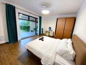 a bedroom with a white bed and a large window at Forest City Golf Course Resort Villa by Lions Bay in Gelang Patah