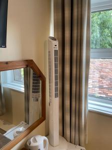 een kamer met een spiegel en een radiator naast een raam bij The Bell Inn in Salisbury