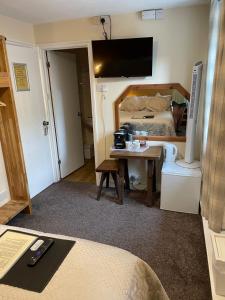 een slaapkamer met een bed, een bureau en een televisie bij The Bell Inn in Salisbury