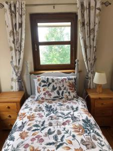 a bedroom with a bed with a floral comforter and a window at 2 Ballyloskey Road in Carndonagh