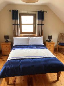 una camera da letto con un grande letto blu e bianco con finestra di 2 Ballyloskey Road a Carndonagh