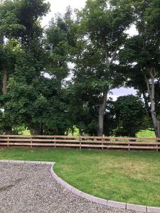 a wooden fence in a park with trees and grass at 2 Ballyloskey Road in Carndonagh