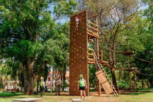 uma mulher em frente a uma torre de escalada num parque em Hotel Fazenda Salto Grande em Araraquara