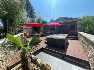 een hot tub op een houten terras met twee rode parasols bij Domaine TerrOcéane in La-Gripperie-Saint-Symphorien